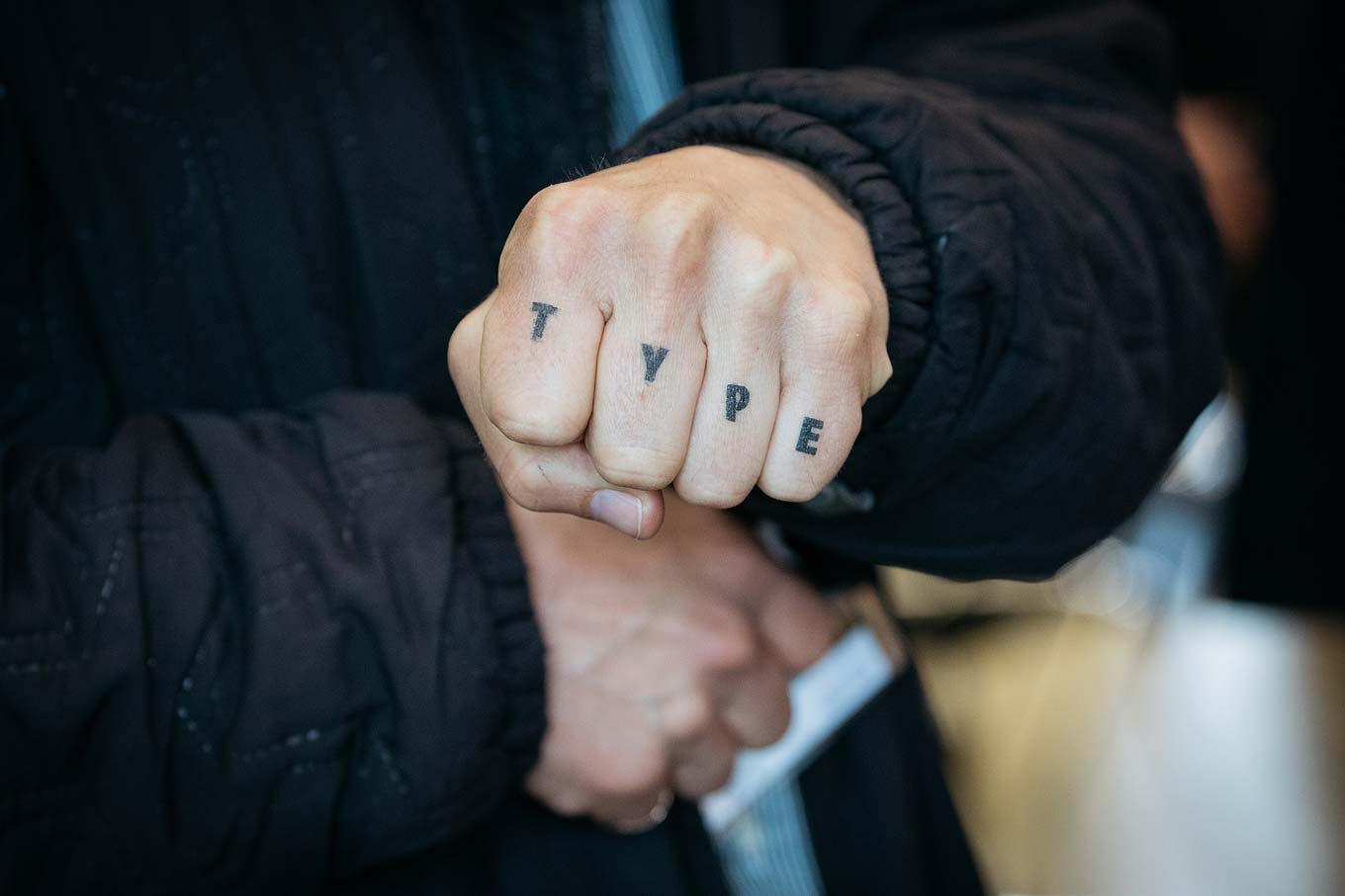 Fist with TYPE tattooed on the four fingers.