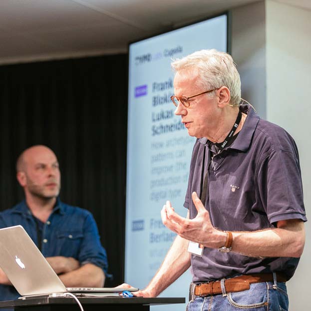 Frank E. Blokland shares the findings of his PhD research, while Lukas Schneider watches in the background.